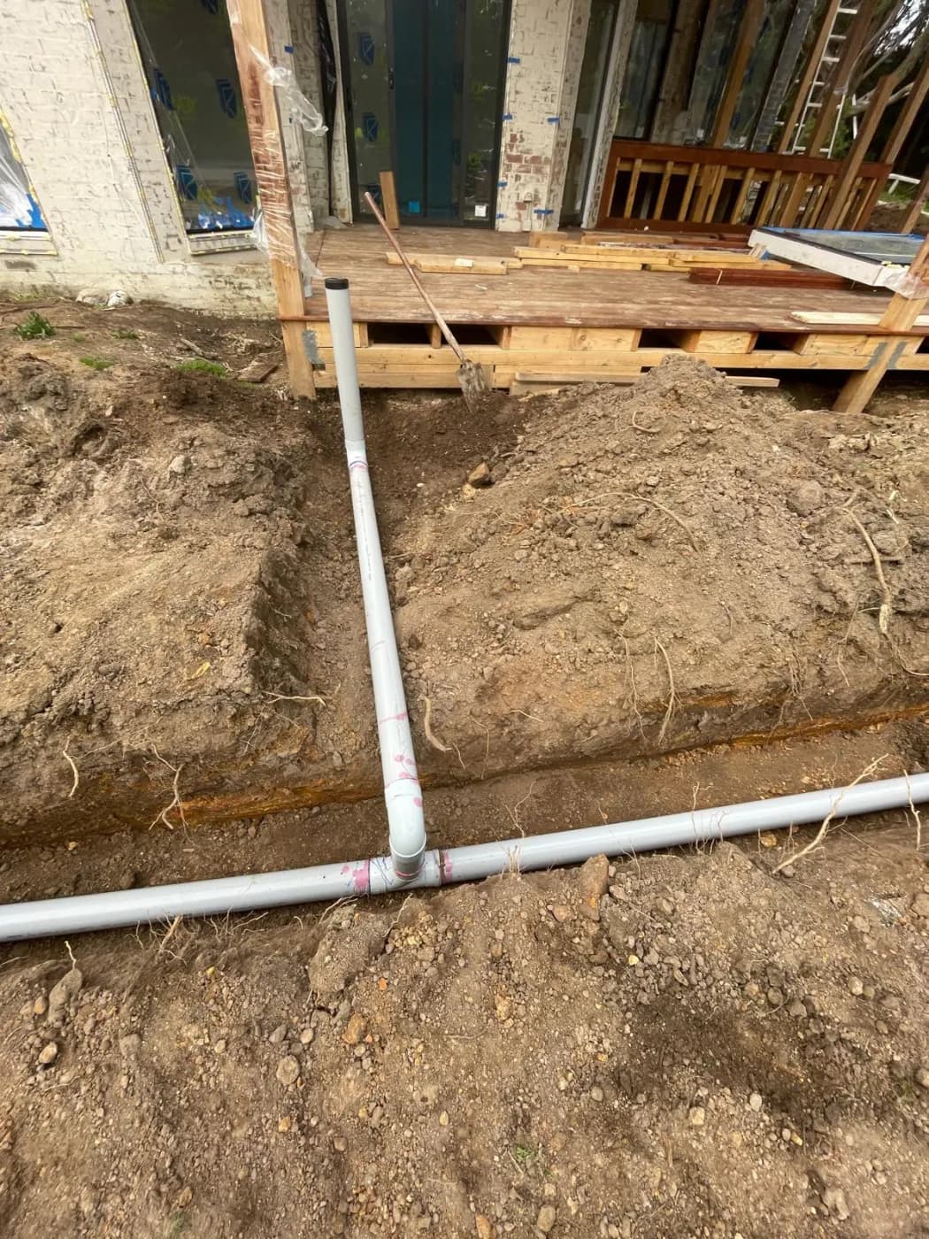 New drainage pipework laid in a trench cut hard against the footings